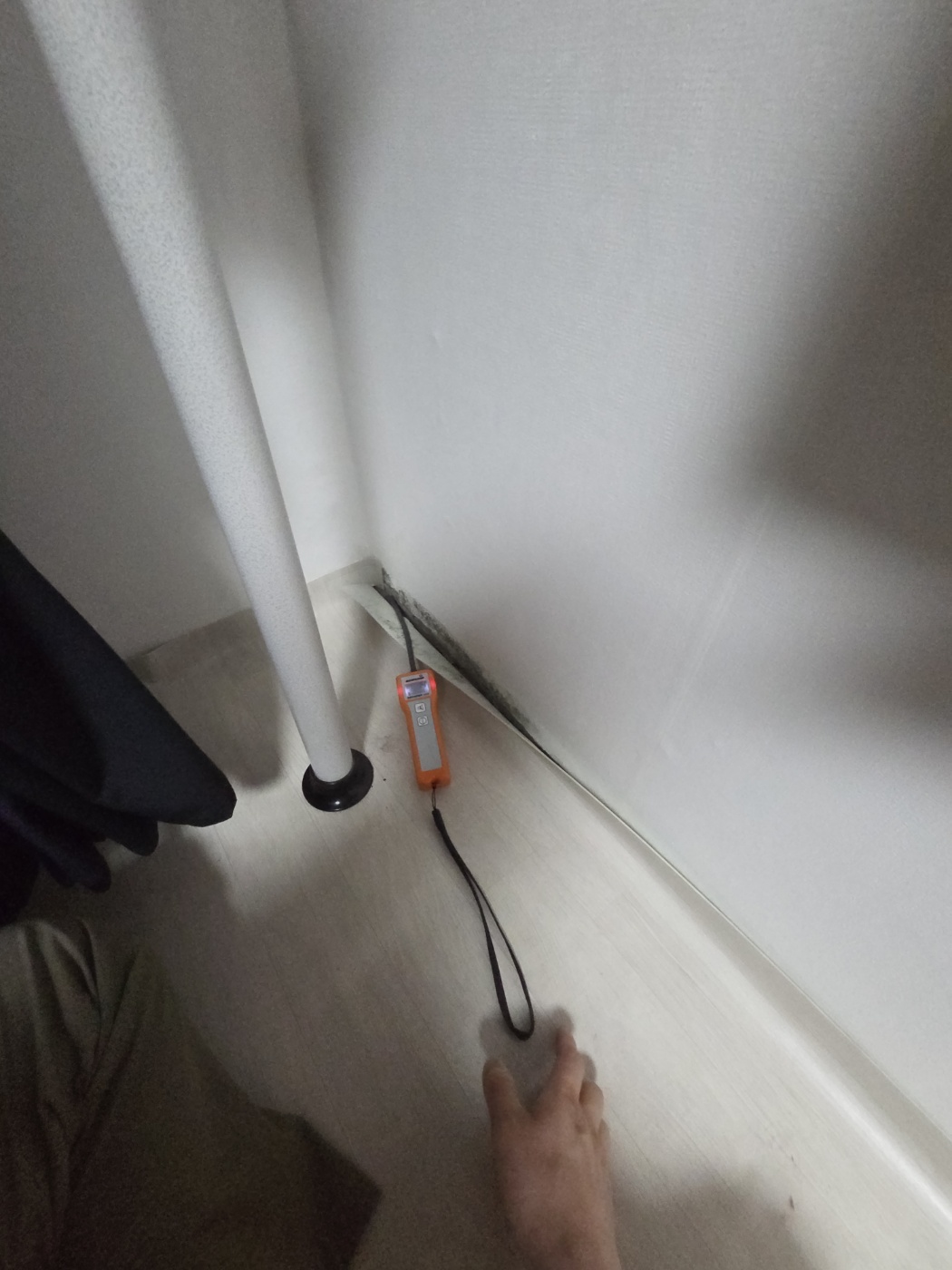 벽과 바닥 경계의 가스 탐지기와 작업자의 손